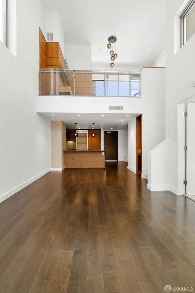 unfurnished living room with dark hardwood / wood-style flooring, a wealth of natural light, and a high ceiling