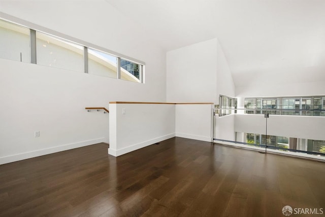 empty room with vaulted ceiling and dark hardwood / wood-style floors