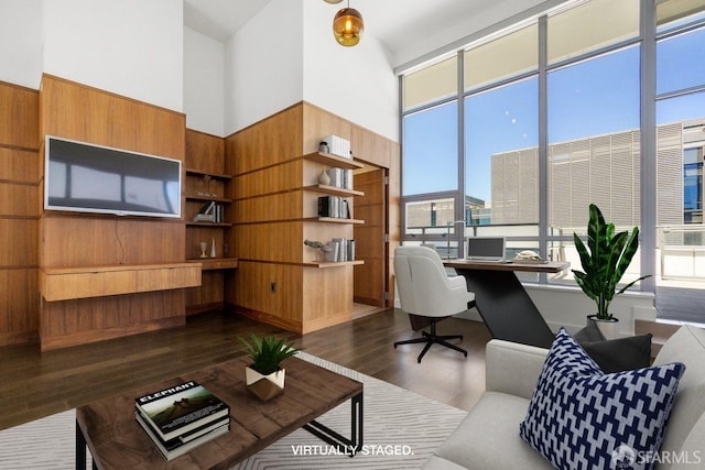 home office with dark hardwood / wood-style flooring, wooden walls, built in desk, and a high ceiling