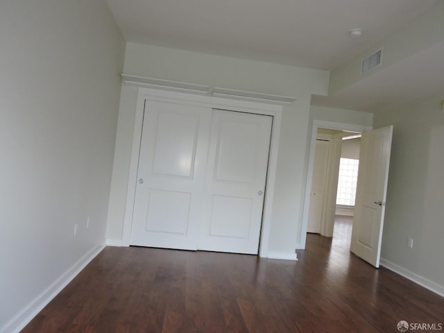 unfurnished bedroom with dark hardwood / wood-style floors and a closet