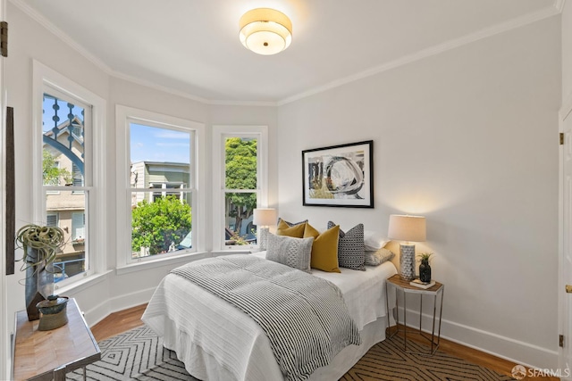bedroom with baseboards, crown molding, and wood finished floors