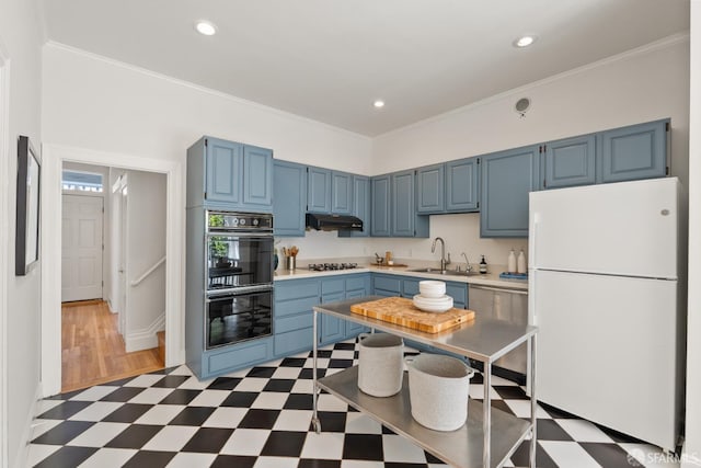 kitchen with freestanding refrigerator, light floors, blue cabinetry, light countertops, and a sink