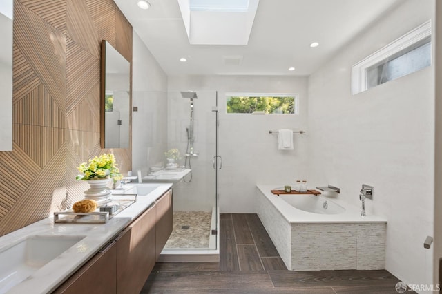 bathroom featuring a shower stall, a bath, wood finished floors, and double vanity