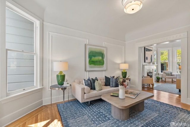 living area with wood finished floors, baseboards, and crown molding
