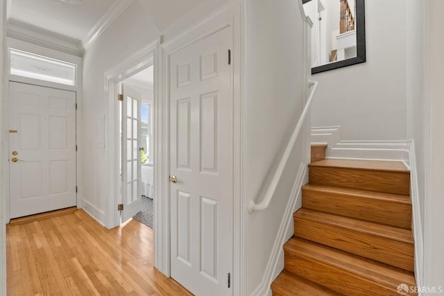 entryway with crown molding, light wood finished floors, and stairs