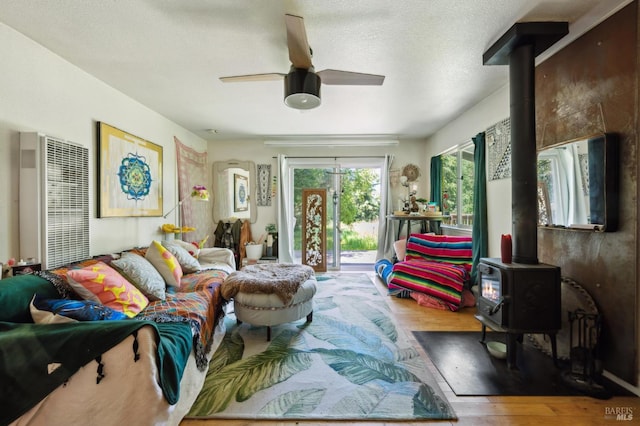 8352 Bodega Ave, Sebastopol, CA 95472 - living area with a wood stove, wood finished floors, ceiling fan, a heating unit, and a textured ceiling