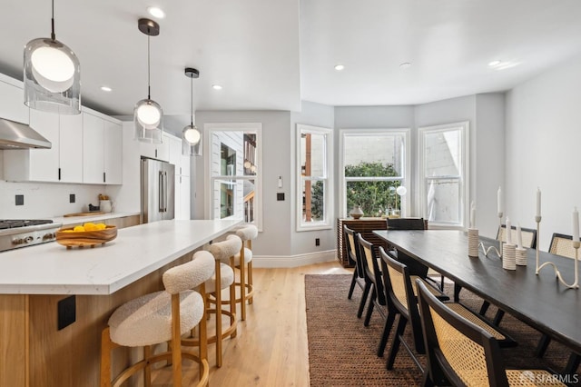1029 Jackson St Unit 1031, San Francisco, CA 94133 - kitchen with stainless steel appliances, a kitchen breakfast bar, light wood-type flooring, baseboards, and white cabinets