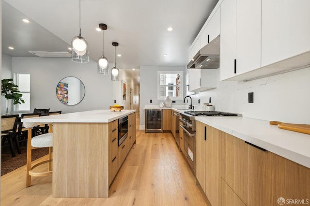 1029 Jackson St Unit 1031, San Francisco, CA 94133 - kitchen featuring modern cabinets, wine cooler, under cabinet range hood, light wood finished floors, and light countertops