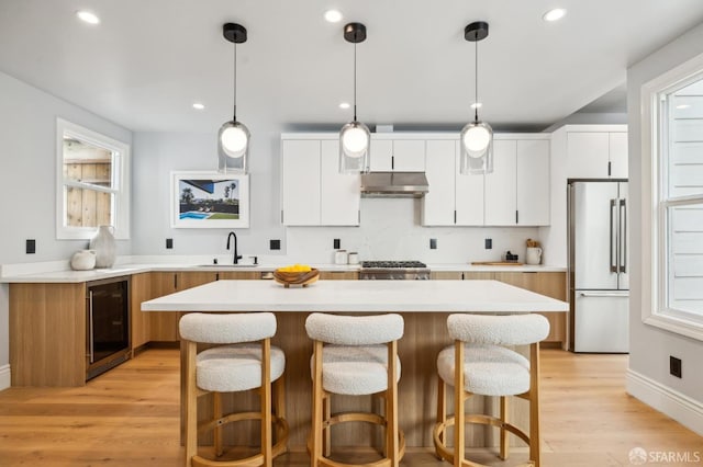 1029 Jackson St Unit 1031, San Francisco, CA 94133 - kitchen featuring freestanding refrigerator, wine cooler, under cabinet range hood, a sink, and a kitchen island