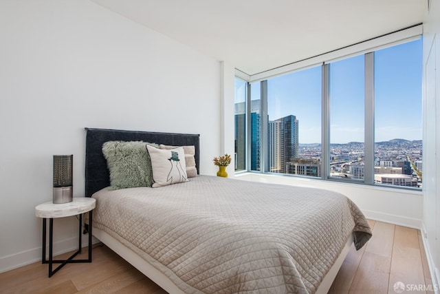 201 Folsom St Unit 38E, San Francisco, CA 94105 - bedroom with multiple windows, wood finished floors, and a city view