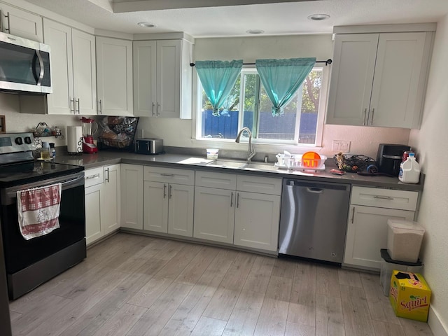 6517 Filaree Way, Sacramento, CA 95842 - kitchen with appliances with stainless steel finishes, a sink, light wood-style flooring, dark countertops, and recessed lighting