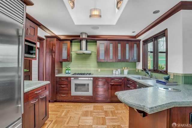 kitchen featuring stainless steel appliances, sink, backsplash, and wall chimney exhaust hood