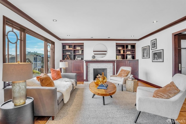 living room with ornamental molding, built in features, and a high end fireplace