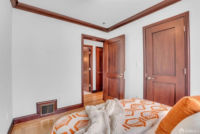 bedroom featuring crown molding and light hardwood / wood-style flooring