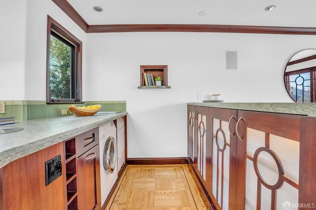 clothes washing area featuring washer / dryer, ornamental molding, and light parquet flooring