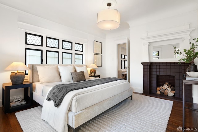 bedroom with a tile fireplace and dark hardwood / wood-style floors