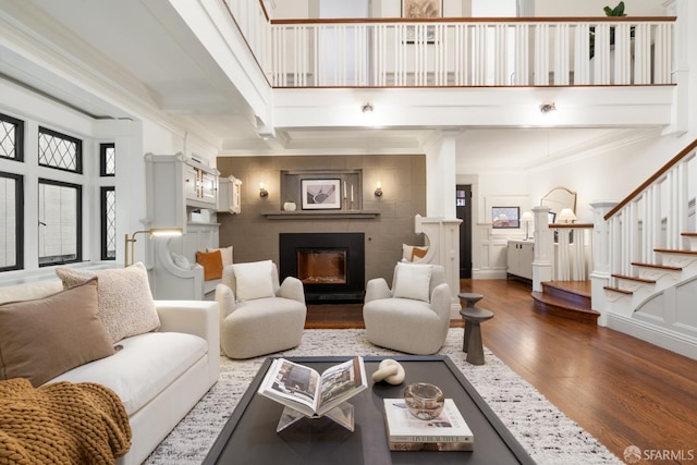 living room featuring beamed ceiling, dark hardwood / wood-style flooring, ornamental molding, and a tiled fireplace