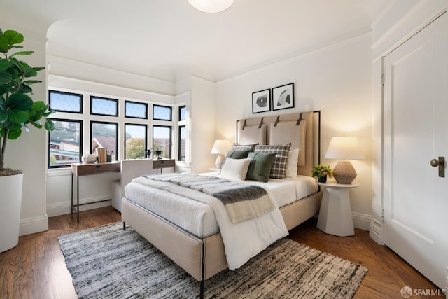 bedroom with dark hardwood / wood-style floors and ornamental molding