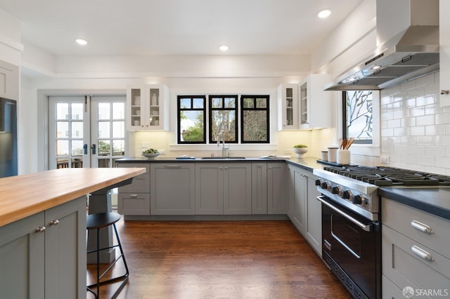 kitchen with wall chimney range hood, sink, high end stainless steel range, dark hardwood / wood-style floors, and gray cabinets