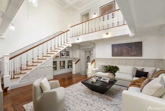 living room featuring beam ceiling, crown molding, dark hardwood / wood-style flooring, and a high ceiling