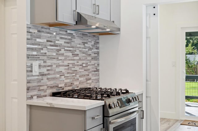 kitchen featuring light hardwood / wood-style flooring, backsplash, stainless steel range oven, and light stone counters