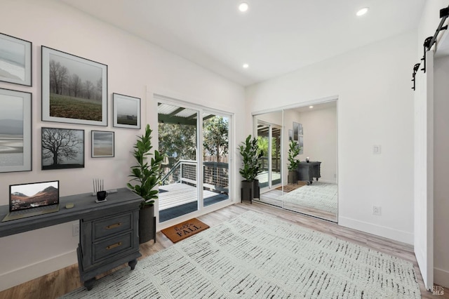 office area with a barn door and light hardwood / wood-style flooring