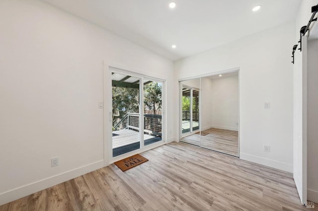 unfurnished room featuring light hardwood / wood-style flooring and a barn door