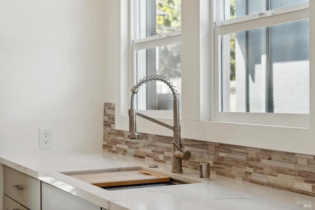 interior details with light stone counters, sink, and decorative backsplash