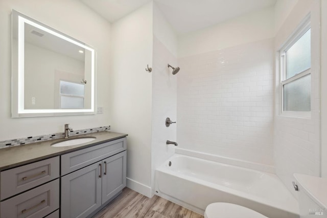 full bathroom with tiled shower / bath combo, vanity, toilet, and hardwood / wood-style flooring