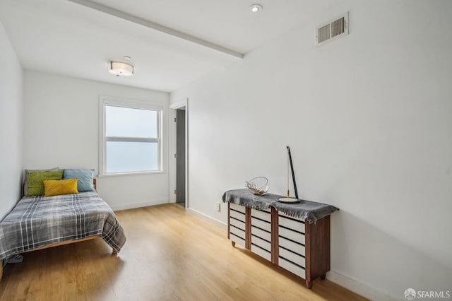 bedroom featuring light hardwood / wood-style flooring and beamed ceiling