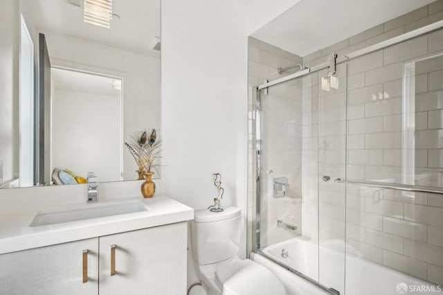 full bathroom featuring toilet, vanity, and shower / bath combination with glass door