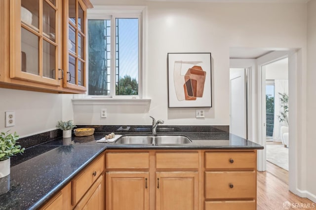 kitchen featuring sink, dark stone counters, and light wood-type flooring