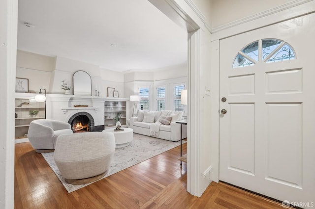 entryway with wood-type flooring and a brick fireplace