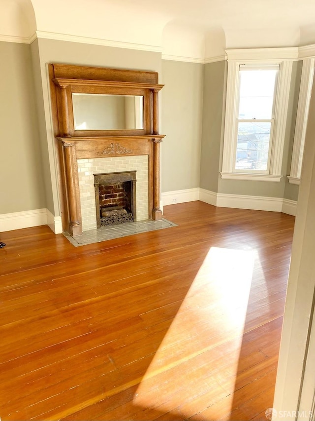 unfurnished living room featuring hardwood / wood-style flooring and ornamental molding