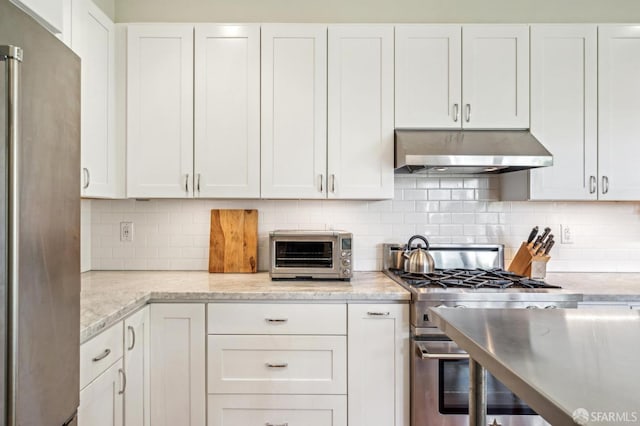 kitchen with decorative backsplash, light stone counters, white cabinetry, and appliances with stainless steel finishes