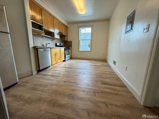 kitchen featuring backsplash, light wood-type flooring, appliances with stainless steel finishes, and crown molding