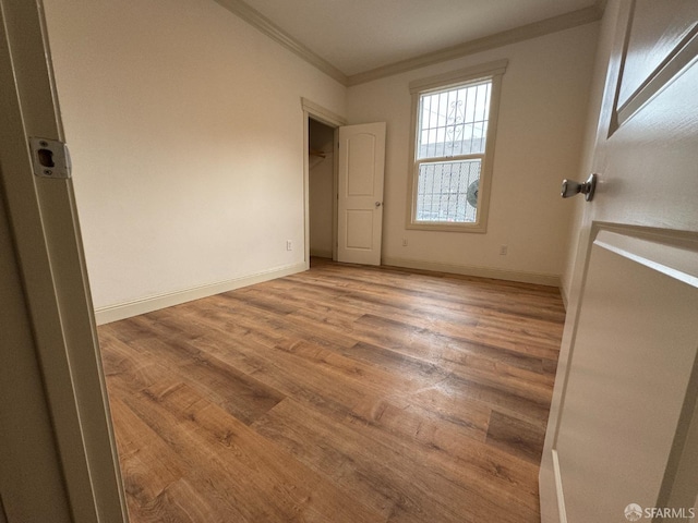 empty room with hardwood / wood-style flooring and ornamental molding