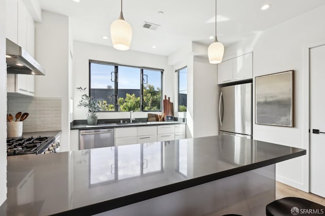 kitchen featuring sink, appliances with stainless steel finishes, pendant lighting, decorative backsplash, and white cabinets