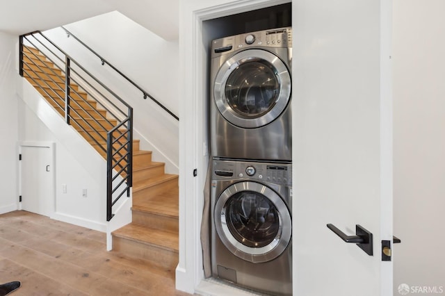 washroom with wood-type flooring and stacked washer / drying machine