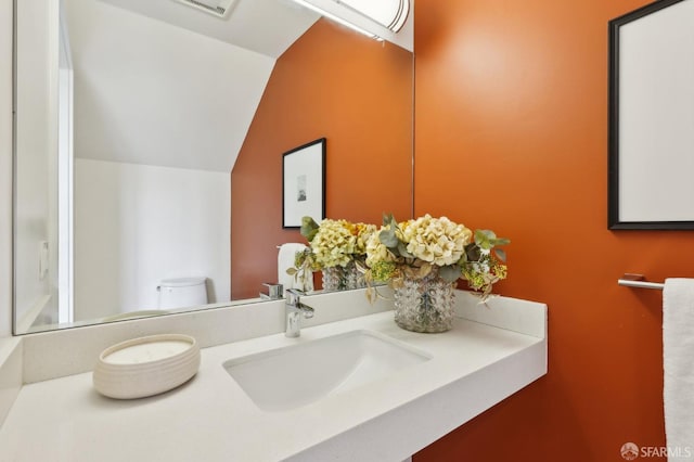 bathroom featuring vanity, vaulted ceiling, and toilet