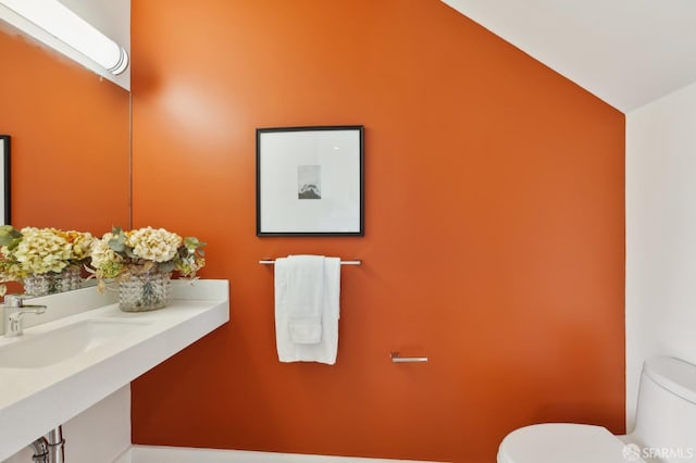 bathroom with lofted ceiling, sink, and toilet