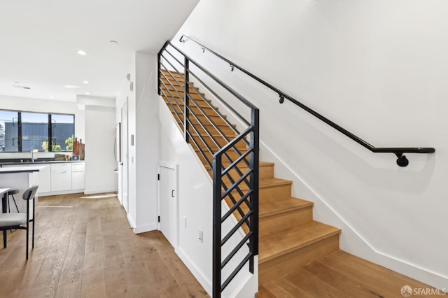 stairs featuring hardwood / wood-style flooring and sink