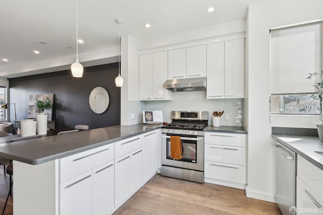 kitchen with stainless steel appliances, white cabinets, decorative light fixtures, kitchen peninsula, and light wood-type flooring