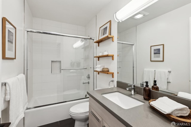 full bathroom featuring vanity, shower / bath combination with glass door, and toilet