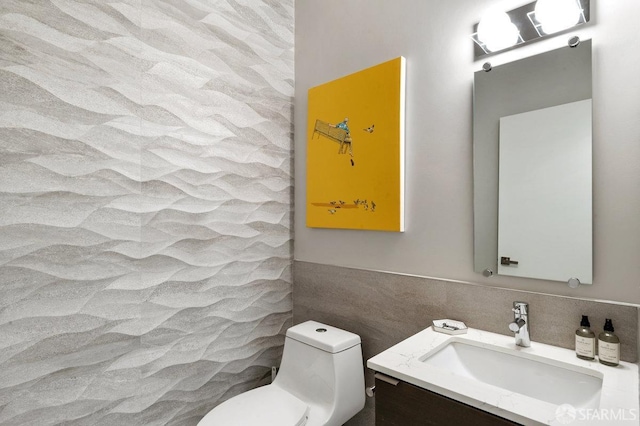 bathroom with vanity, toilet, and tile walls