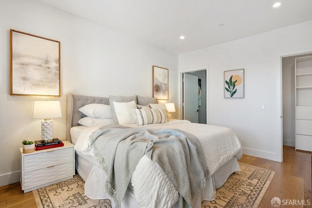 bedroom with a spacious closet and light wood-type flooring