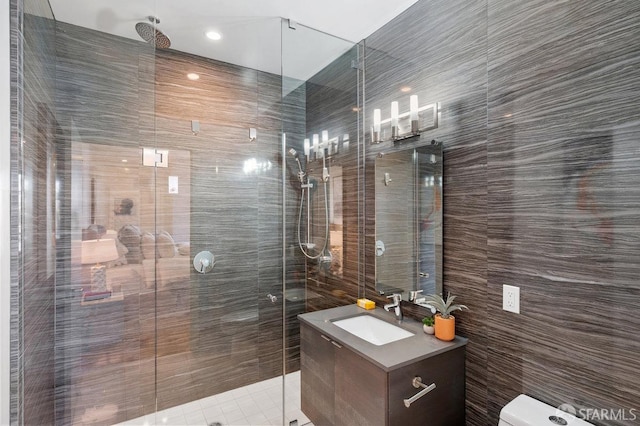 bathroom with tile walls, vanity, toilet, and an enclosed shower