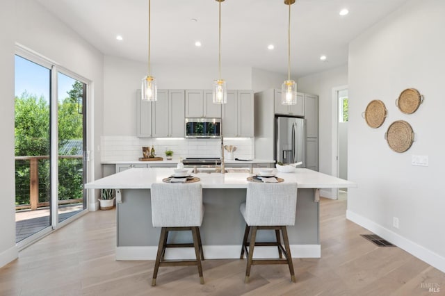745 Redwood Rd, San Anselmo, CA 94960 - kitchen featuring appliances with stainless steel finishes, tasteful backsplash, light countertops, a kitchen island with sink, and a kitchen breakfast bar