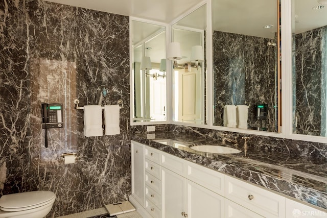 bathroom with vanity, toilet, and tile walls