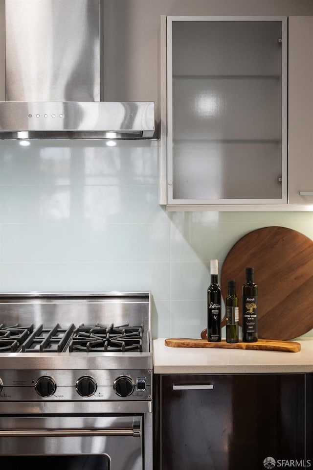 kitchen with decorative backsplash, light countertops, stainless steel range with gas stovetop, and exhaust hood